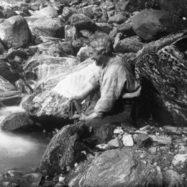 Charlie Douglas washing his shirt in a creek.FranzJosef Glacier.ca.1894.