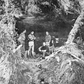 Trampers in a rock bivouac, Flying Horse Creek, South Westland