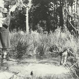 Anna Lucas carrying Hazel Lucas standing by a soda Spring , Kotuku - .1926-27.