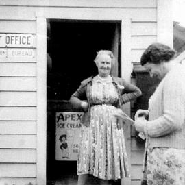 The Mawheraiti Post Office with Postmistress Mrs Elizabeth Summerville at the door