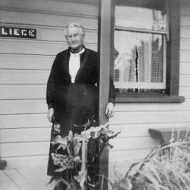 Emilie Hahn, standing on the verandah of the house she lived in in Brick St (now O'Donnell St), Greymouth.