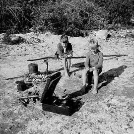 Two boys sitting by a campfire with a portable gramophone, Westland District.1930`s.