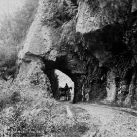A horse and trap passing through the Cave, a stone arch on the road alongside the Buller Gorge.ca.1880-1889.