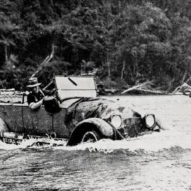 The mail car crossing a shallow stretch of the  Waitangiroto River, near Waiho, Westland