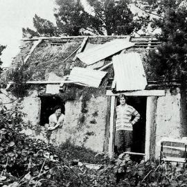  A man and woman inside an old mud hut built by pioneers near Porter's Pass, on the main road to Westland.