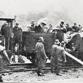 Prime Minister William Massey disembarks the train on a rainy day, after travelling through the Otira Tunnel .1923.
