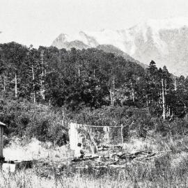 A roadman's hut near the Waiho River, with the Southern Alps in the background.1929.