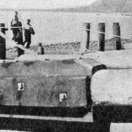 Wharf-building at Jackson Bay - a boy sits beside a pile which has been split to give extra strength.1938.