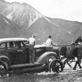A car being hauled across the river on a dray, before the Waimakariri bridge opening.1936.