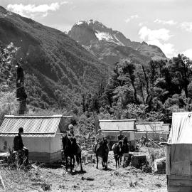 A woman and children on horseback passing through the Public Works camp in the Hollyford Valley.	 1940.