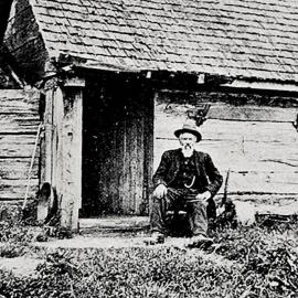 Gold prospector wearing a suit and hat and seated outside his house, The Mangles, Murchison.1923.