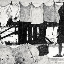 A woman hangs out washing even though the ground was covered in snow.1931.