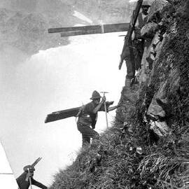 Men carrying timber towards Haast Ridge for building Haast hut.ca.1915.