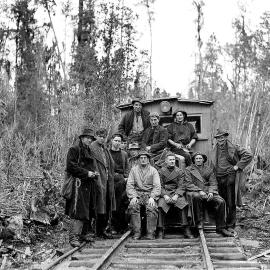 Group portrait of bushmen seated on the back of a locomotive used to transport workers and felled logs between the felling area and the timber mill at Ross.1947.