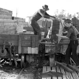 Men loading stacks of timber onto bogies at the Ross timber mill .1947.
