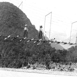 Female trampers on a wire suspension bridge at Waiho Gorge.1913.